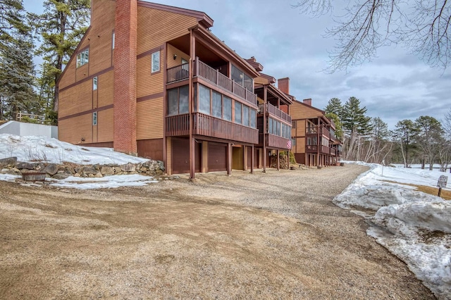 snow covered building with gravel driveway and a garage