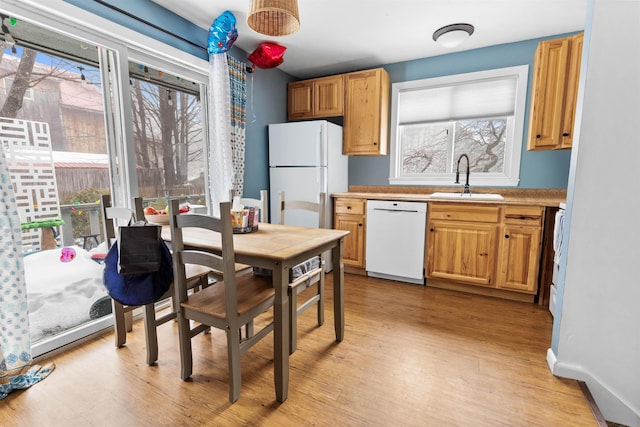 kitchen featuring white appliances, light wood-type flooring, baseboards, and a sink