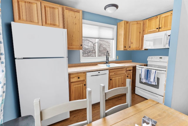 kitchen with a sink, white appliances, light brown cabinets, and light countertops