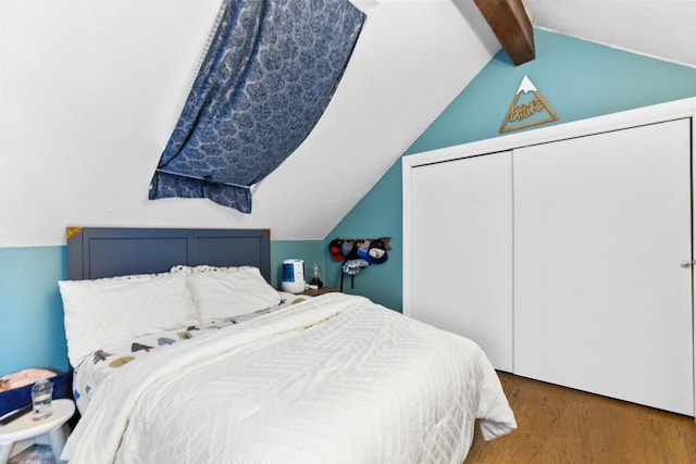 bedroom with a closet, wood finished floors, and vaulted ceiling with beams