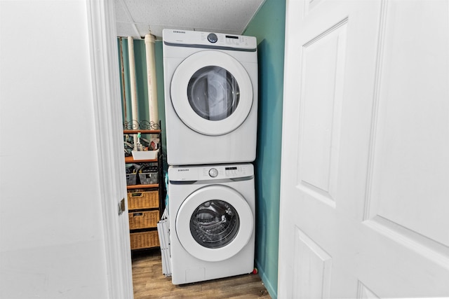 laundry area with laundry area, stacked washer / drying machine, and wood finished floors