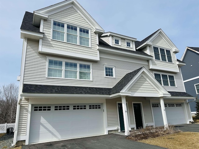 view of front of house featuring aphalt driveway, an attached garage, central AC unit, and roof with shingles