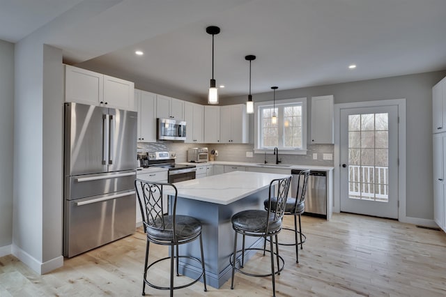 kitchen featuring tasteful backsplash, a kitchen bar, light stone counters, appliances with stainless steel finishes, and a sink