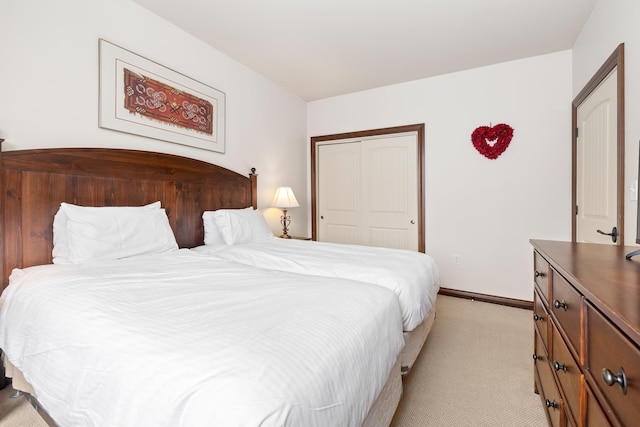 bedroom featuring light carpet, baseboards, and a closet