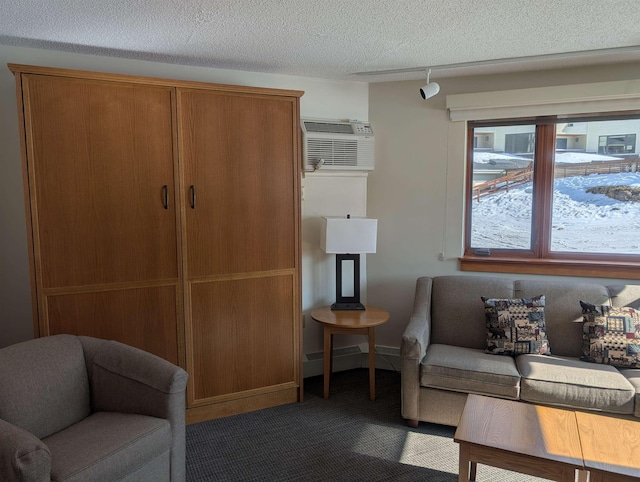 living area featuring rail lighting, carpet, a wall mounted air conditioner, and a textured ceiling