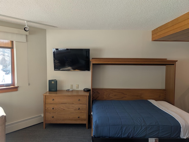 carpeted bedroom featuring a baseboard heating unit, baseboards, and a textured ceiling