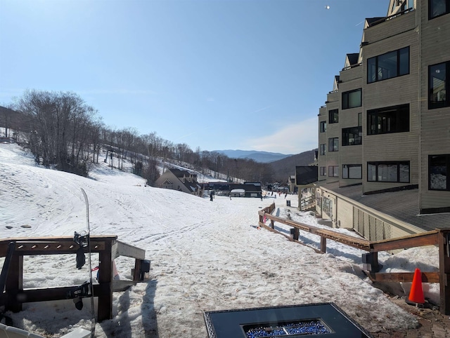 yard covered in snow featuring a mountain view