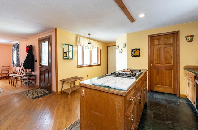 39 Birch Glen Dr, Bennington, NH 03442 - kitchen featuring dark wood-style floors, a center island, brown cabinetry, baseboards, and stainless steel gas cooktop