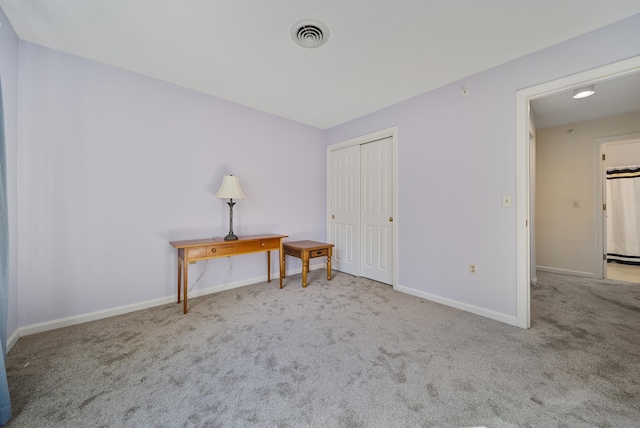 interior space with a closet, visible vents, carpet flooring, and baseboards