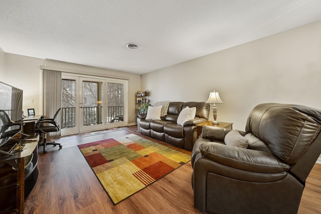 living area with visible vents, a textured ceiling, and wood finished floors