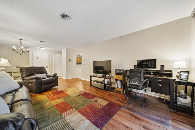 living room with visible vents, baseboards, a notable chandelier, and wood finished floors