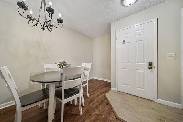 dining space featuring a chandelier, light wood finished floors, a textured ceiling, and baseboards