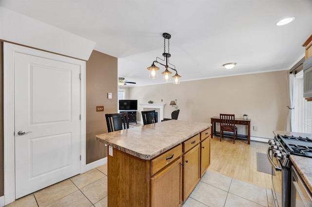 kitchen featuring a kitchen island, gas range, light tile patterned floors, hanging light fixtures, and a ceiling fan