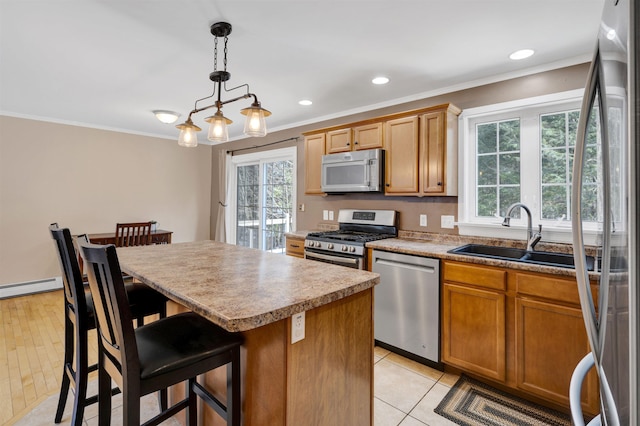 kitchen featuring a healthy amount of sunlight, stainless steel appliances, crown molding, and a sink