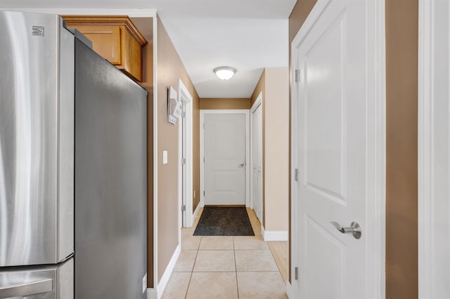 hallway featuring light tile patterned floors and baseboards