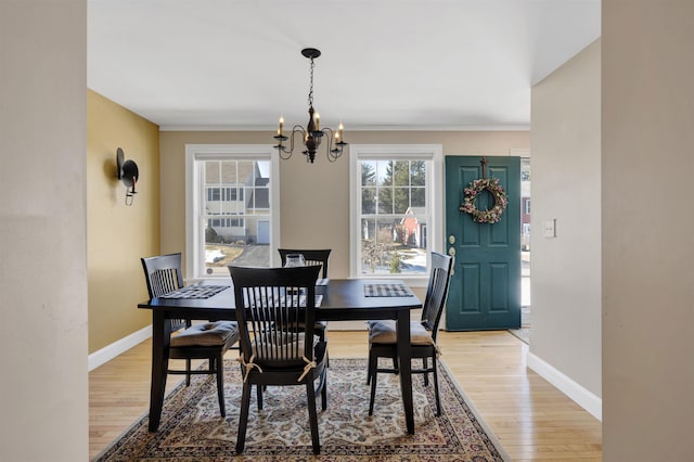 dining space featuring light wood-style floors, baseboards, and a chandelier