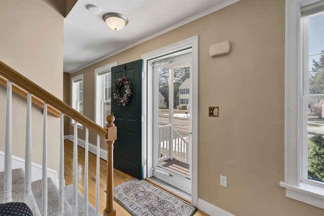 foyer entrance with stairway, baseboards, ornamental molding, and light wood finished floors