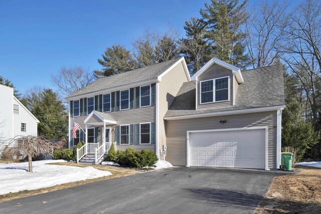 colonial house with a garage, driveway, and a shingled roof