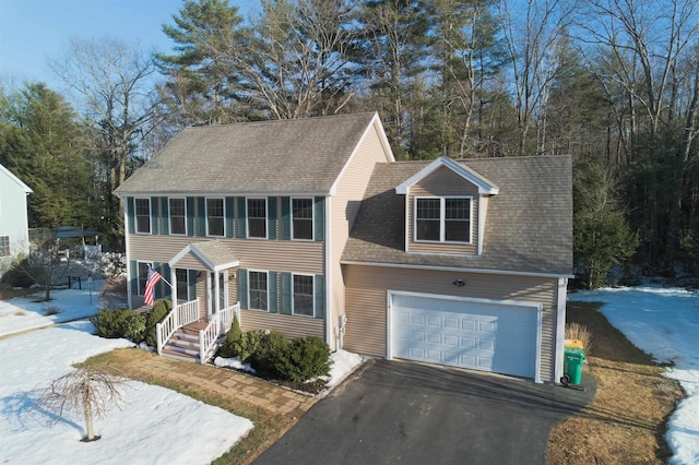 colonial house featuring an attached garage, driveway, and a shingled roof