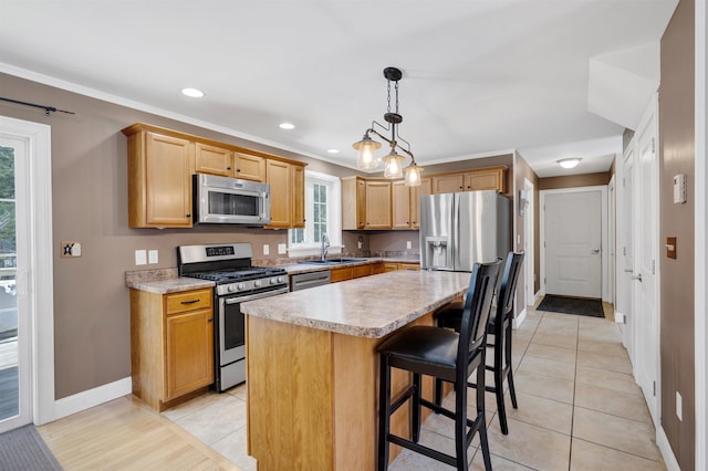 kitchen featuring a kitchen island, decorative light fixtures, a breakfast bar area, light countertops, and stainless steel appliances