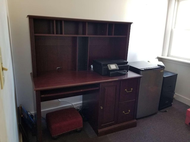 carpeted office space with built in study area and baseboards