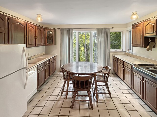 kitchen with a sink, white appliances, light tile patterned flooring, and light countertops