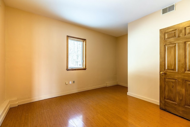 empty room featuring visible vents, baseboards, and wood finished floors
