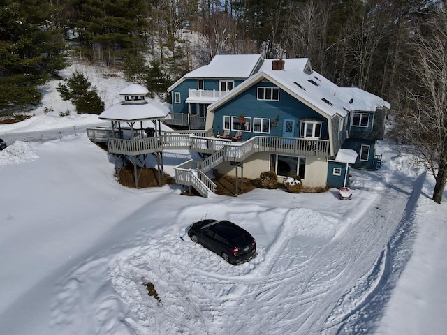 snow covered back of property featuring stairway and a balcony