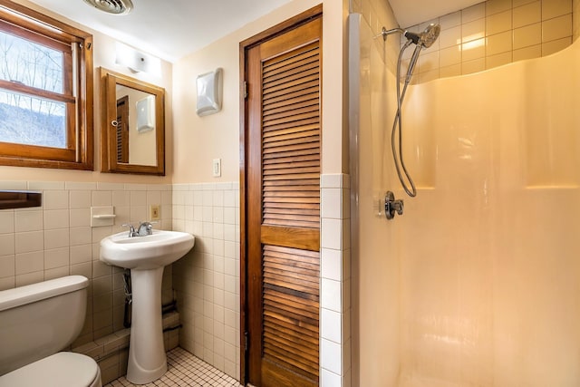 full bath featuring a shower stall, a wainscoted wall, toilet, tile walls, and a sink