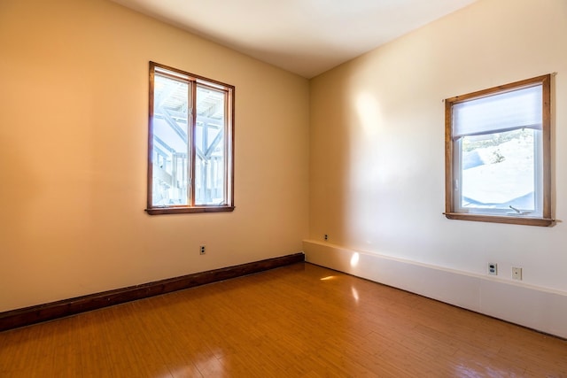 spare room featuring baseboards and wood finished floors