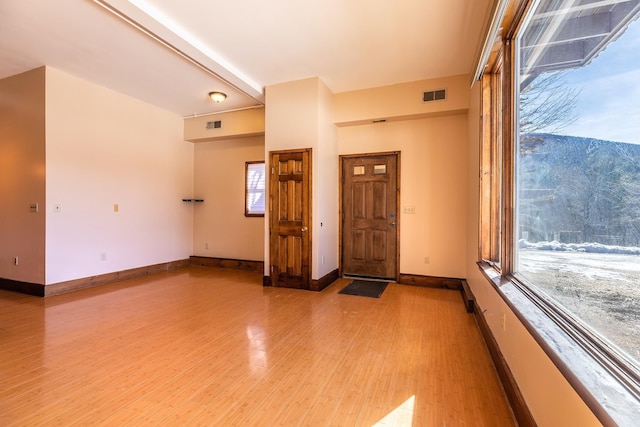 interior space with light wood-style floors, visible vents, and baseboards