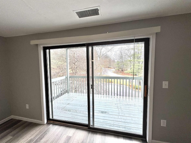 doorway to outside featuring visible vents, baseboards, and wood finished floors