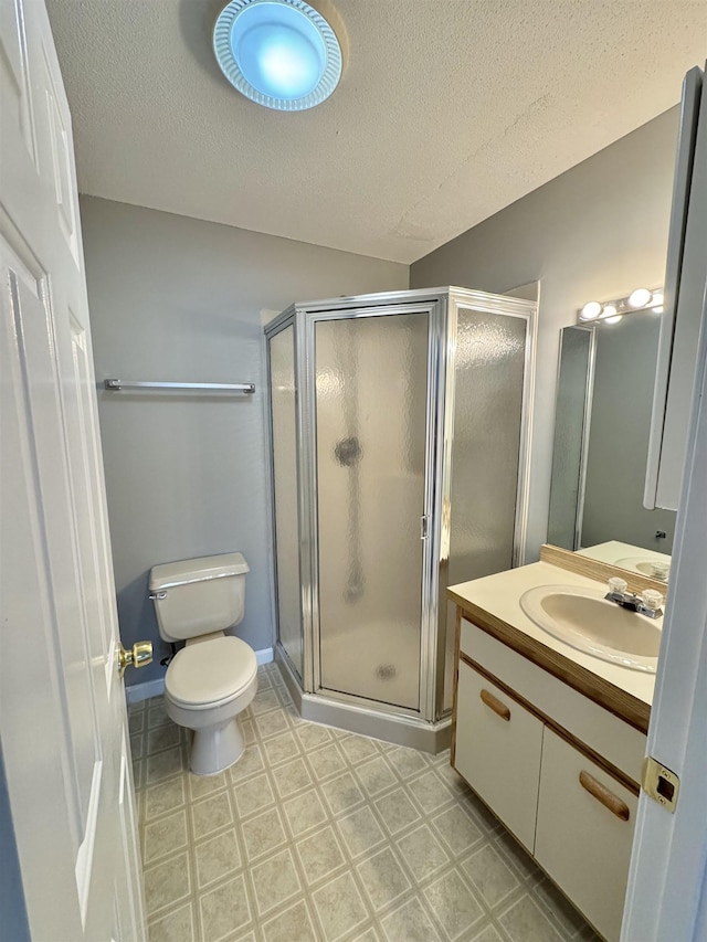 bathroom with a shower stall, toilet, vanity, tile patterned floors, and a textured ceiling