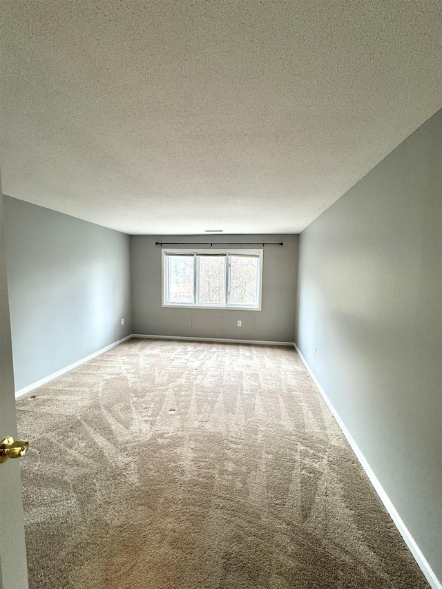 carpeted empty room with a textured ceiling and baseboards