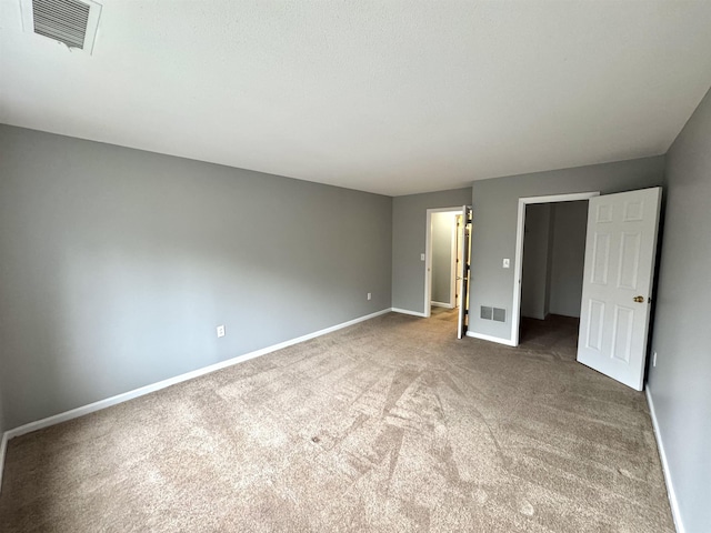 unfurnished bedroom featuring visible vents, baseboards, carpet, and a walk in closet