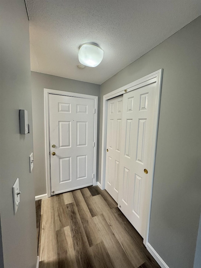 doorway to outside with dark wood-style floors, baseboards, and a textured ceiling