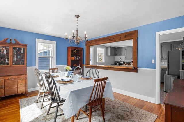 dining space with an inviting chandelier, wood finished floors, and baseboards