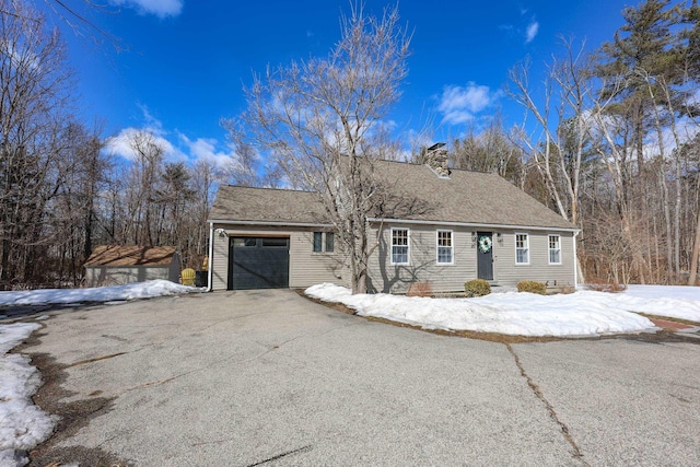 view of front of home featuring a shingled roof, a garage, driveway, and a chimney