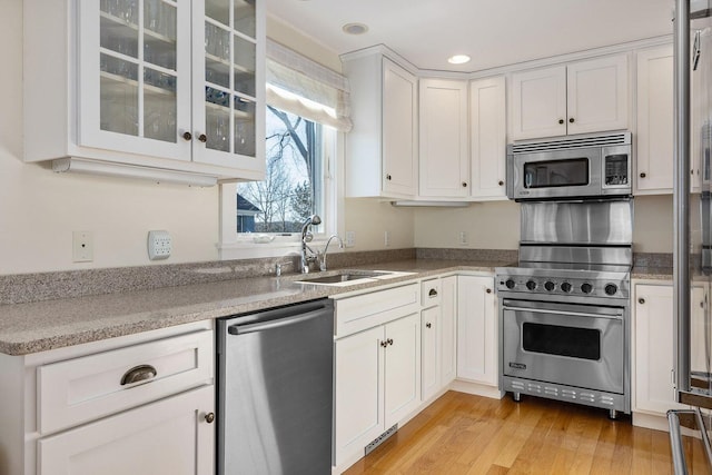 kitchen featuring light wood-style flooring, appliances with stainless steel finishes, white cabinets, and glass insert cabinets