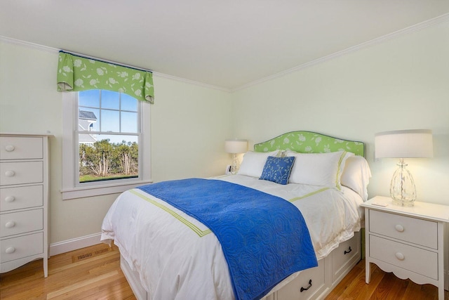 bedroom with crown molding, light wood-style floors, baseboards, and visible vents