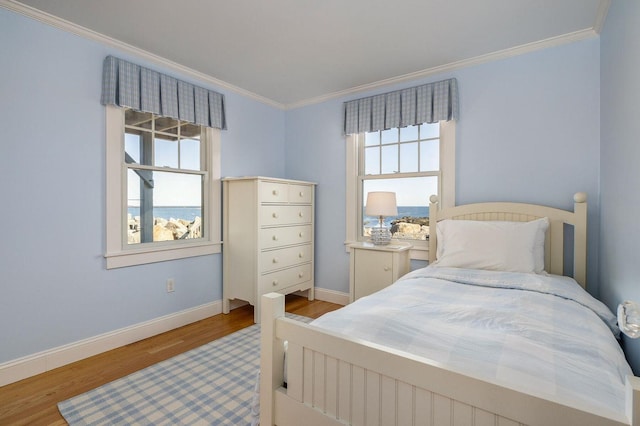 bedroom with wood finished floors, baseboards, and ornamental molding