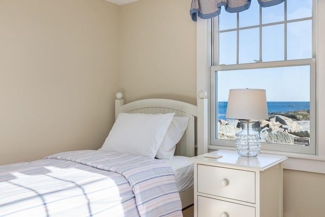 bedroom with multiple windows and a water view