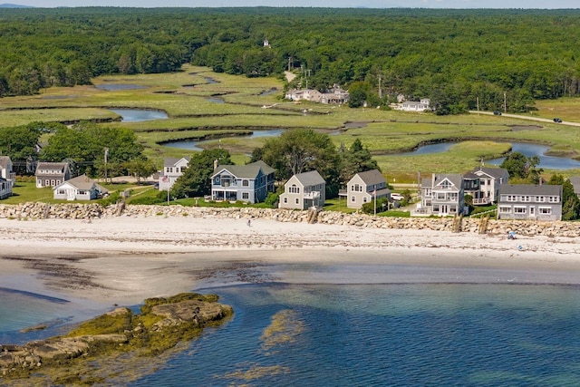 drone / aerial view featuring a view of the beach, a wooded view, and a water view