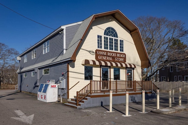 view of front of house featuring a gambrel roof and roof with shingles