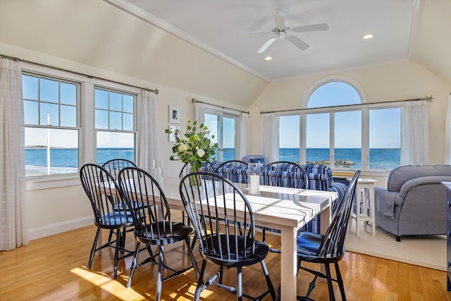 dining room featuring vaulted ceiling, a ceiling fan, a water view, and light wood finished floors