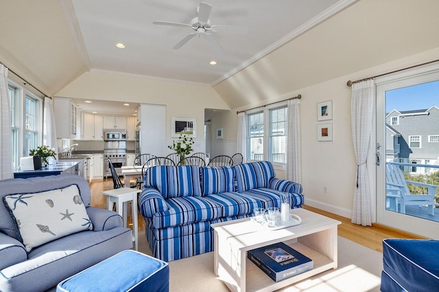 living room with lofted ceiling, light wood-style floors, ornamental molding, and a ceiling fan