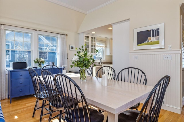 dining space with a wealth of natural light, light wood-type flooring, lofted ceiling, and ornamental molding