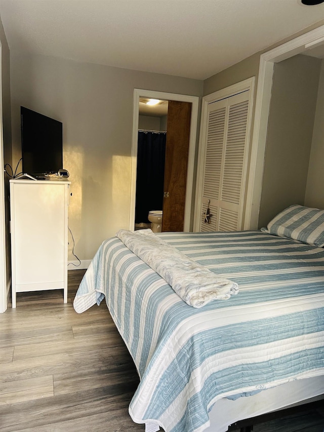 bedroom with ensuite bath, a closet, and wood finished floors