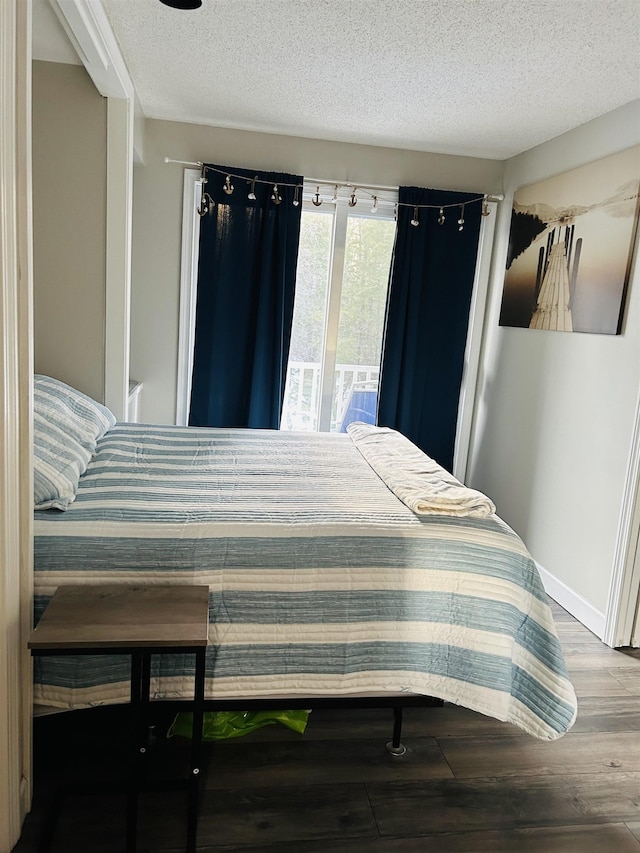 bedroom with baseboards, wood finished floors, and a textured ceiling