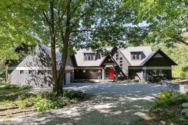 view of front of property featuring gravel driveway, an attached garage, and metal roof